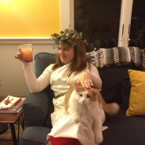 Me in my toga, awaiting partygoers. I picked the picture where the cat looks most annoyed. Yes, that is real ivy on my head.